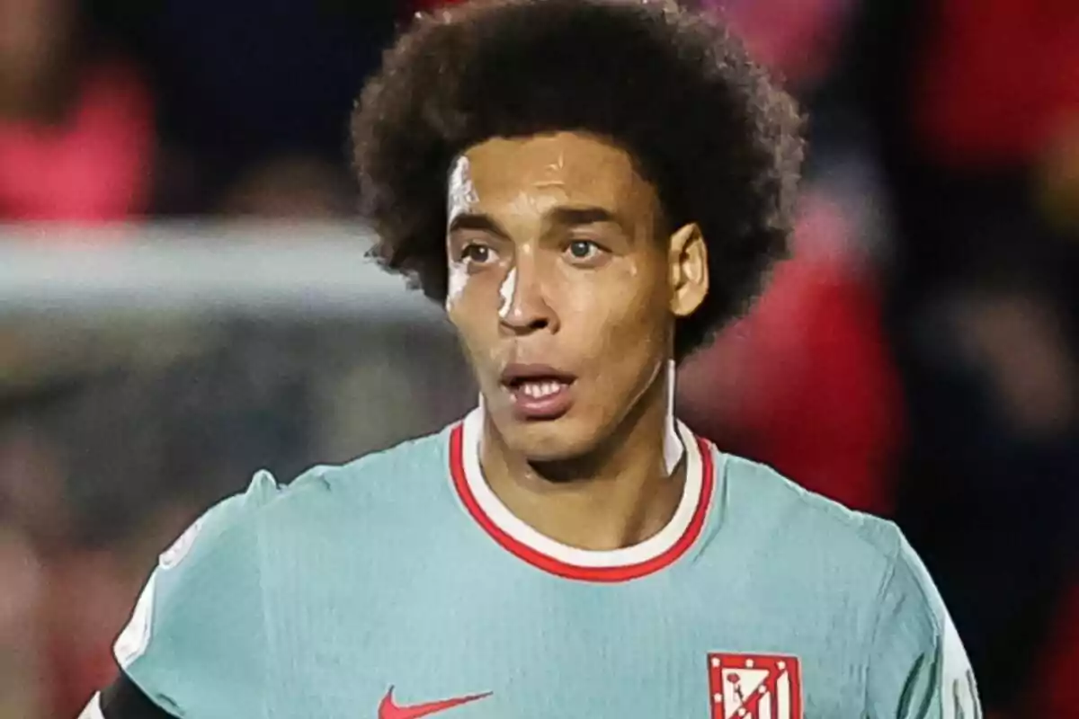 Un jugador de fútbol con uniforme celeste y escudo del Atlético de Madrid en el campo.