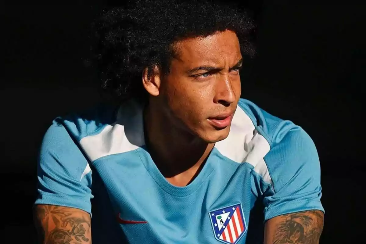 Jugador de fútbol con camiseta azul del Atlético de Madrid mirando hacia la derecha.