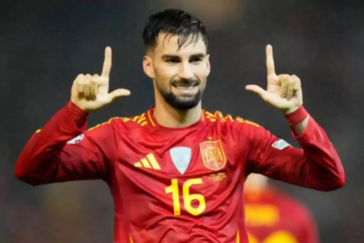 Jugador de fútbol con la camiseta de España número 16 celebrando con las manos levantadas.