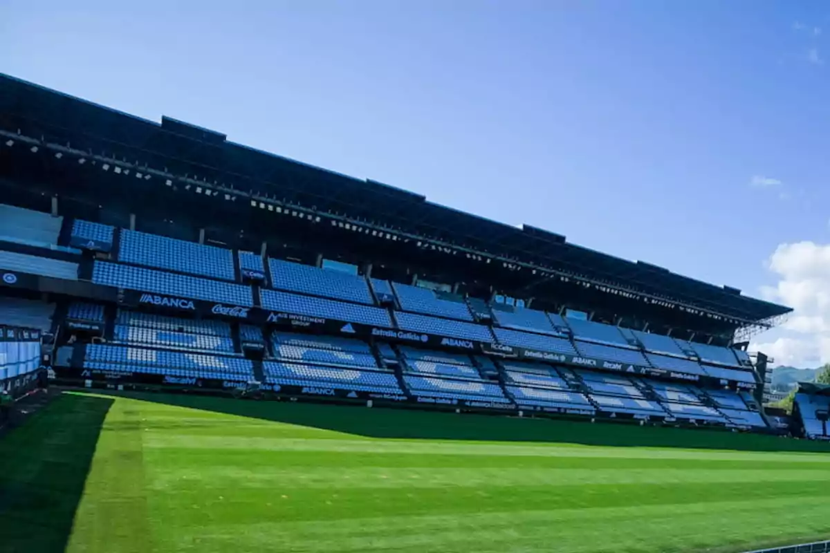 Estadio de fútbol vacío con gradas y césped verde.