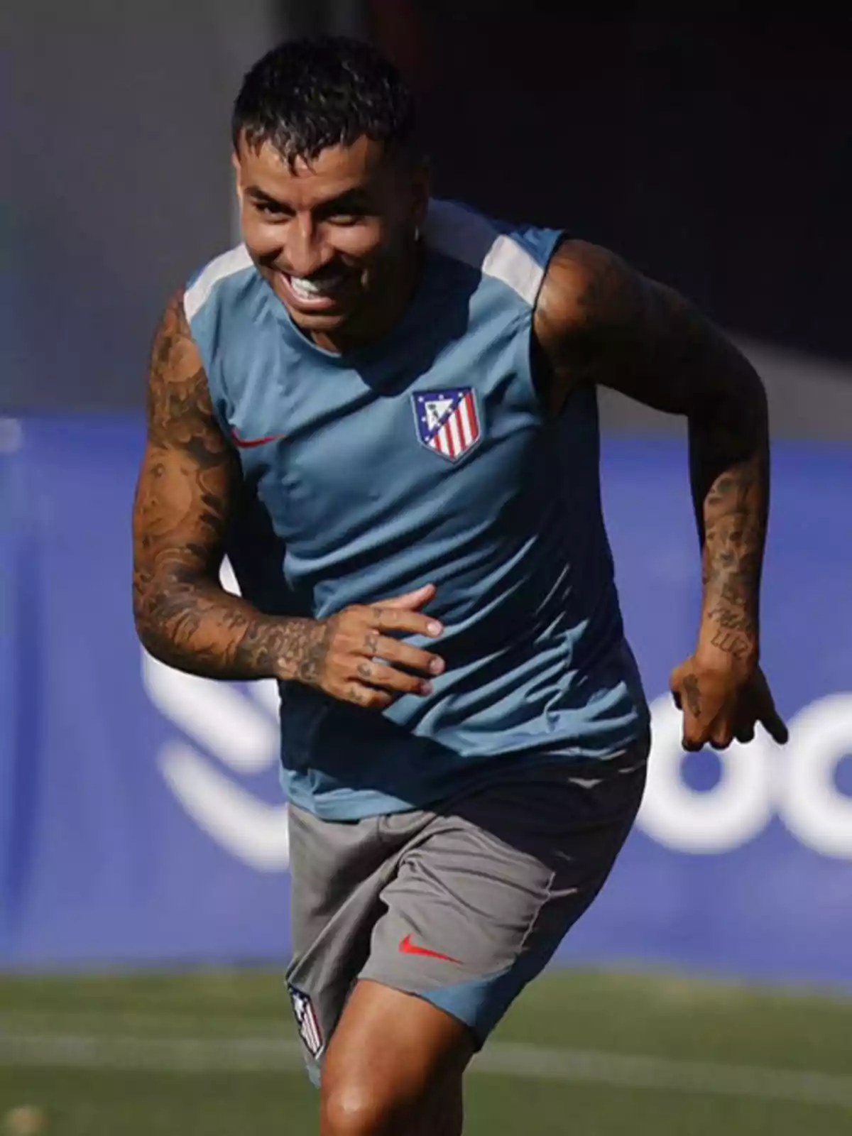 A football player in Atletico Madrid training uniform running on a field. A football player in Atletico Madrid training uniform running on a field.