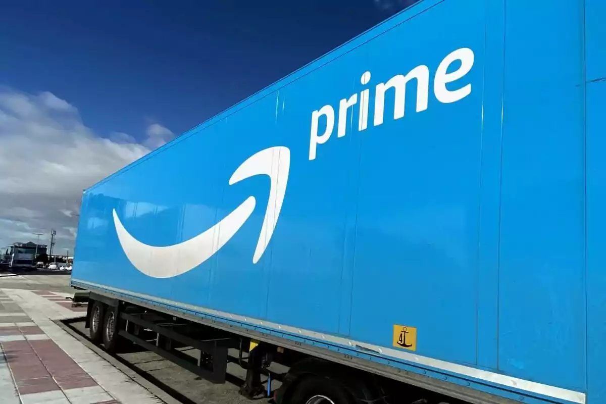 A blue truck with the Amazon logo in a parking lot under a partly cloudy sky. A blue truck with the Amazon logo in a parking lot under a partly cloudy sky.