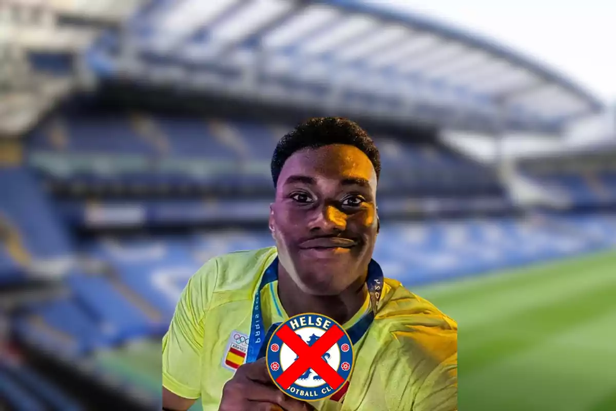 Un hombre sonriente con una medalla y un símbolo tachado de un equipo de fútbol en un estadio.