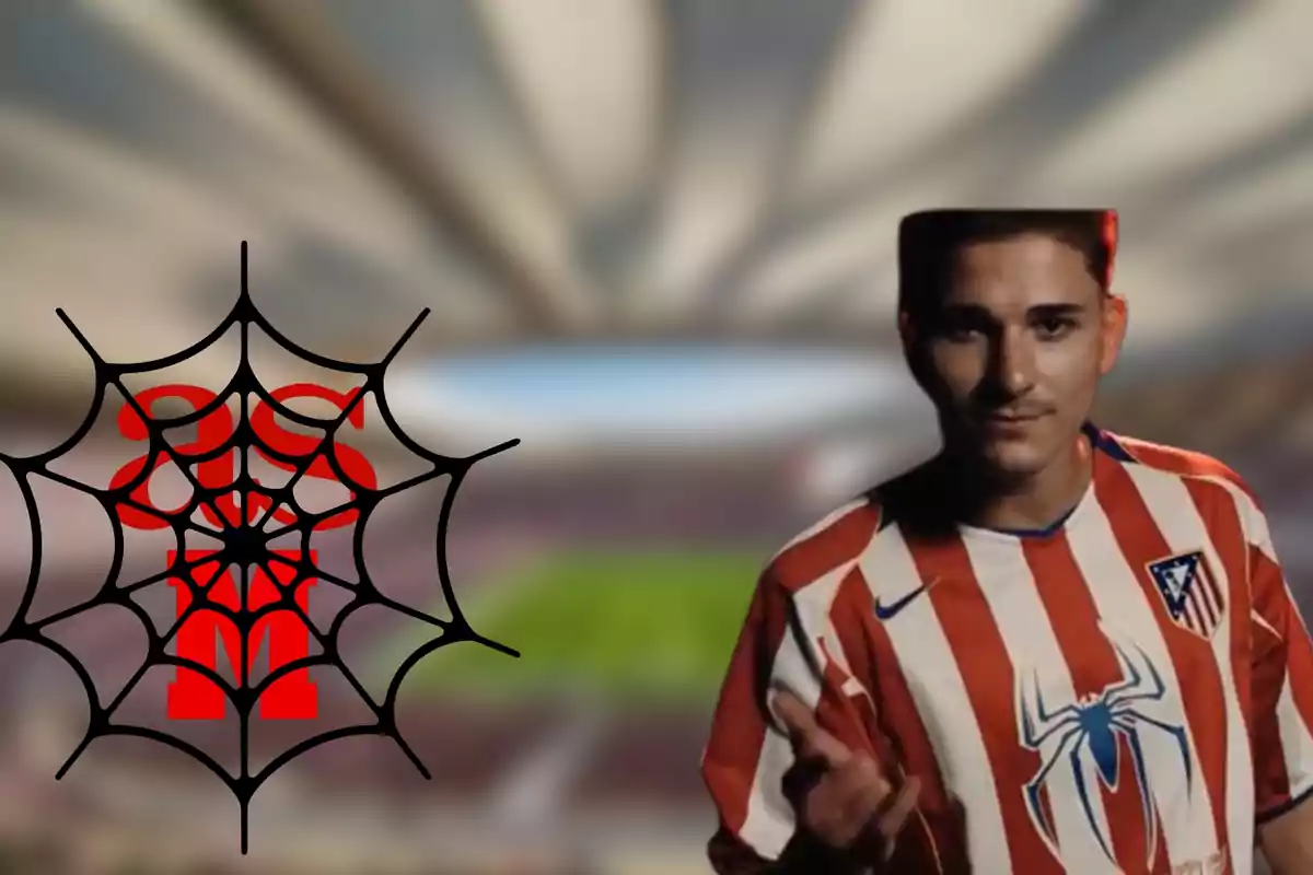 Un hombre con una camiseta de fútbol del Atlético de Madrid con un diseño de araña en el pecho, junto a una telaraña negra con un símbolo rojo en el centro, en un estadio de fútbol desenfocado.