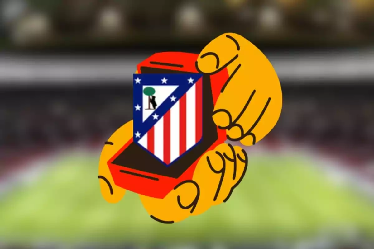 Manos sosteniendo una caja roja con el escudo del Atlético de Madrid en un estadio de fútbol desenfocado.