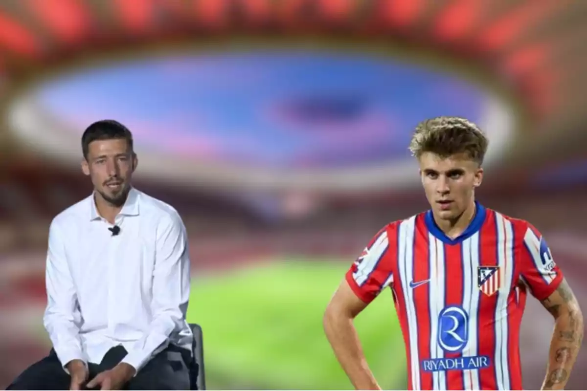 Dos hombres, uno sentado con camisa blanca y otro de pie con uniforme de fútbol del Atlético de Madrid, con un estadio desenfocado de fondo.