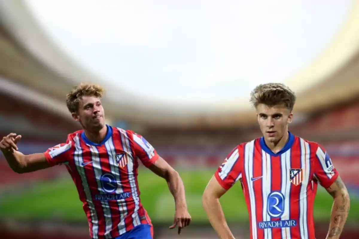 Dos jugadores de fútbol con el uniforme del Atlético de Madrid en un estadio.