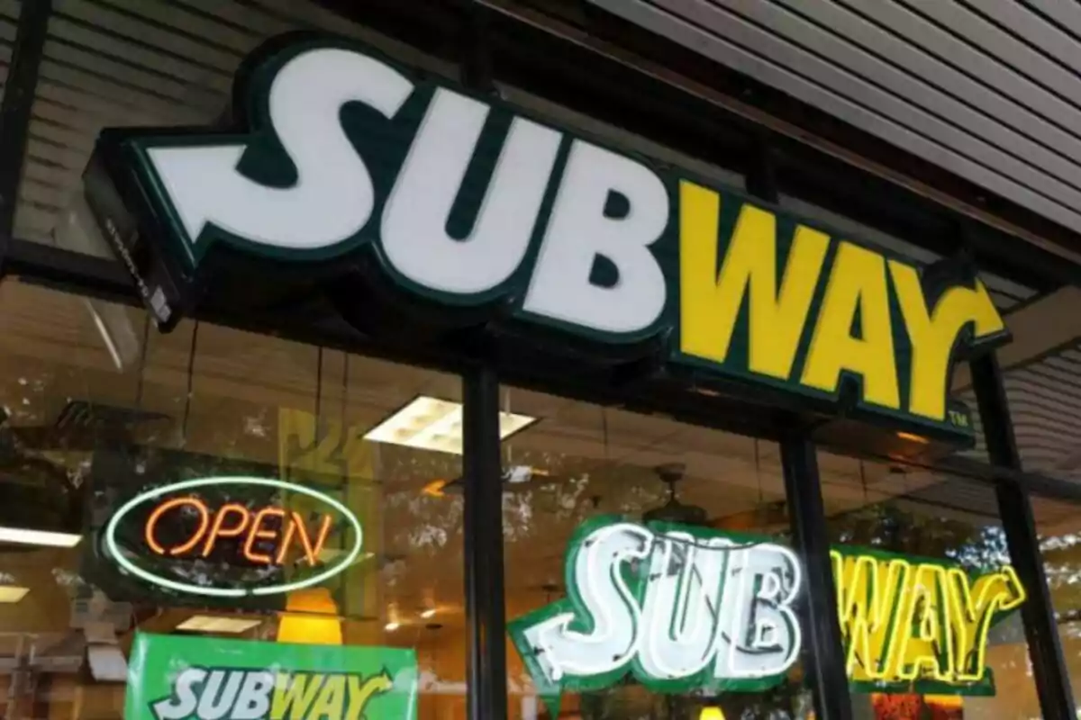 Un letrero de un restaurante de comida rápida, que es Subway, con luces de neón que indican que está abierto. Un letrero de un restaurante de comida rápida, que es Subway, con luces de neón que indican que está abierto.