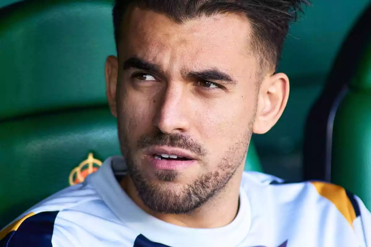 Dani Ceballos mirando a un costado mientras está sentado en el banquillo del Betis