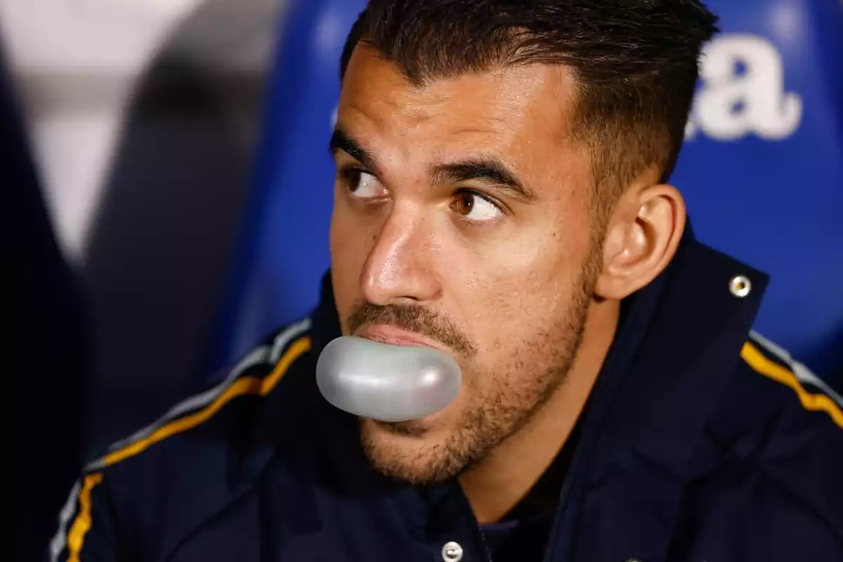 Dani Ceballos haciendo una pompa con un chicle mientras está sentado en el banquillo