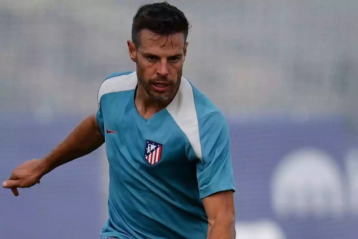 Jugador de fútbol con camiseta de entrenamiento del Atlético de Madrid en acción.