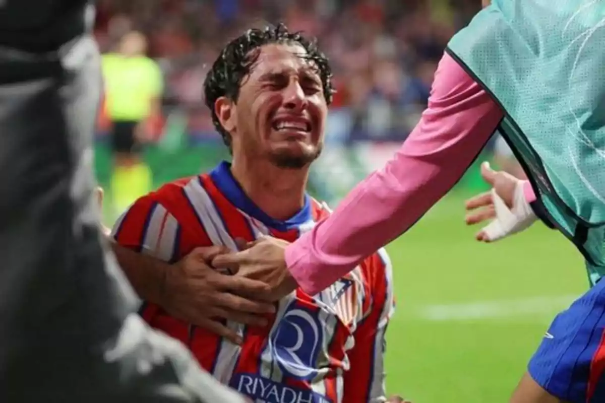 A soccer player crying while being comforted by a teammate on the field. A soccer player crying while being comforted by a teammate on the field.