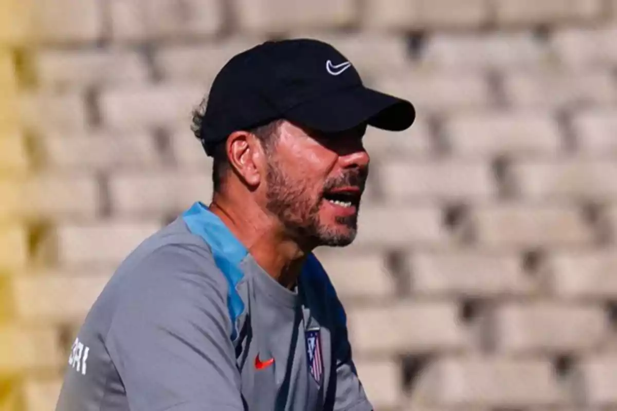 Un hombre con gorra negra y camiseta gris con el logo del Atlético de Madrid.