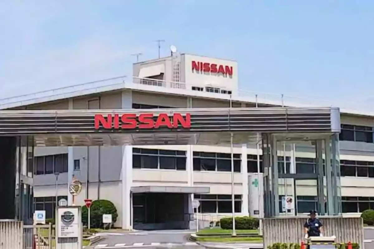 Fachada de una planta industrial de Nissan con el logo en letras rojas sobre la entrada principal Fachada de una planta industrial de Nissan con el logo en letras rojas sobre la entrada principal