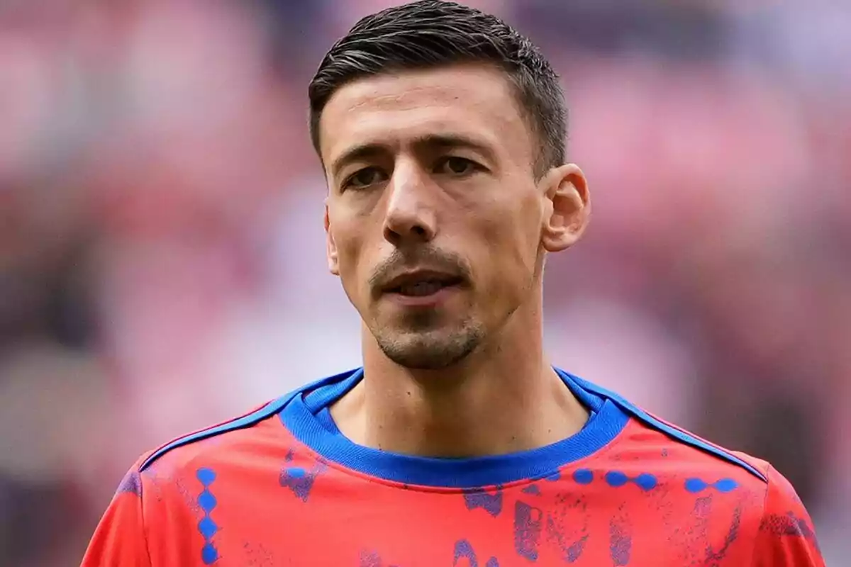 Un jugador de fútbol con camiseta roja y azul en un estadio.