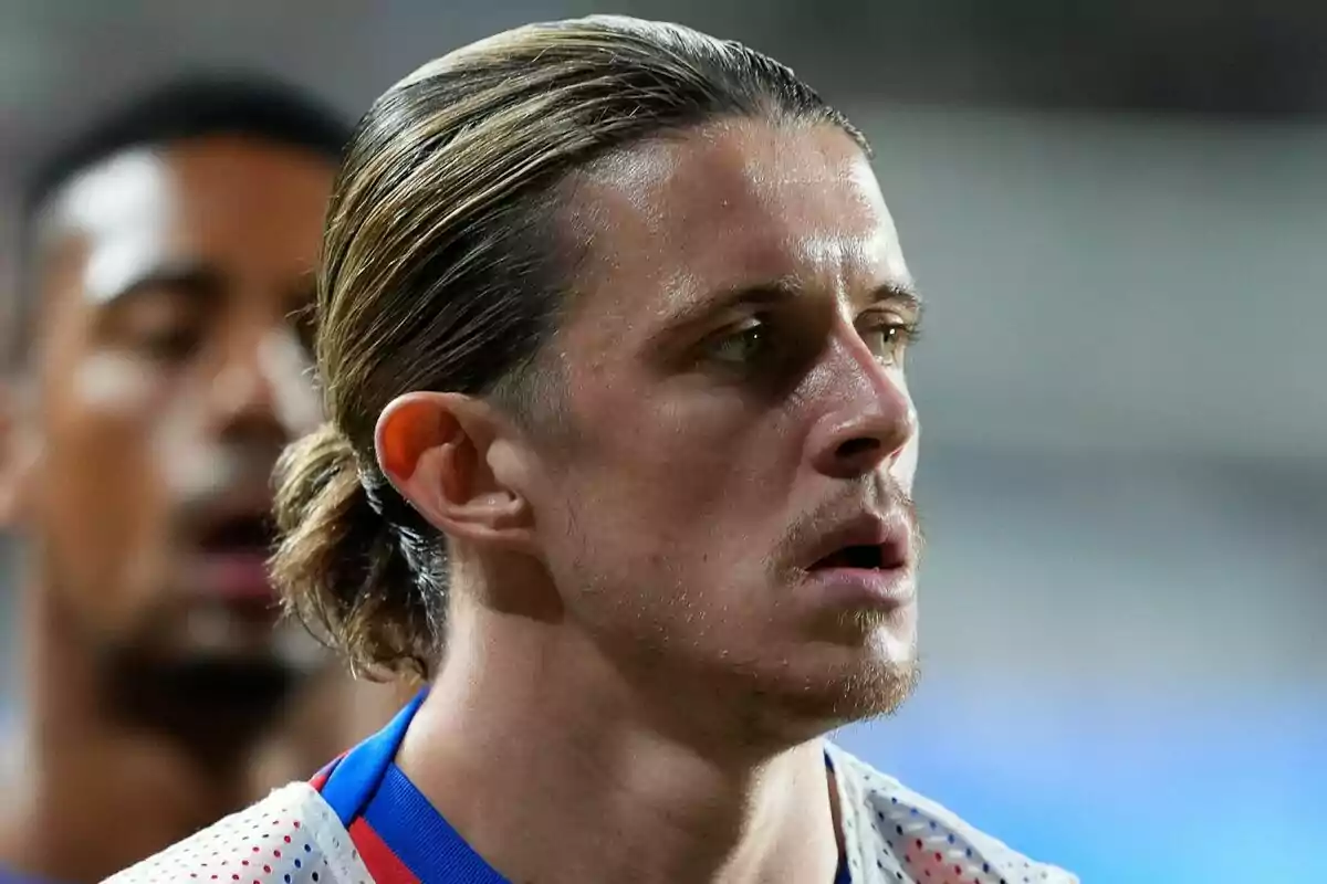 Un jugador de fútbol con el cabello recogido y una expresión seria durante un partido.