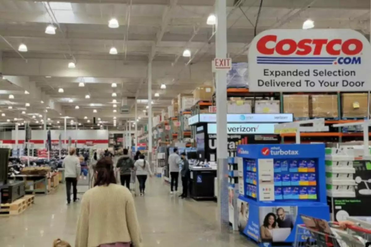 People walking inside a Costco store with tall shelves full of products and signs of different brands