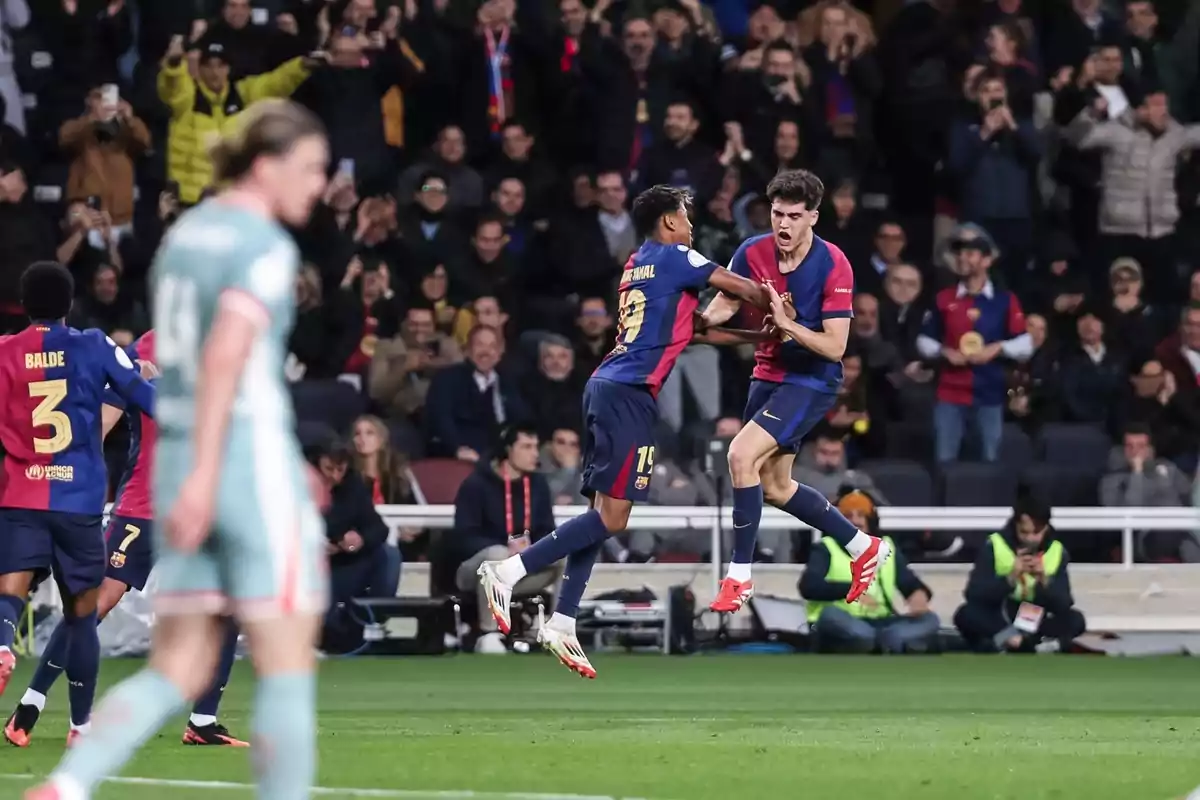 Jugadores de fútbol celebrando un gol en un estadio lleno de aficionados.