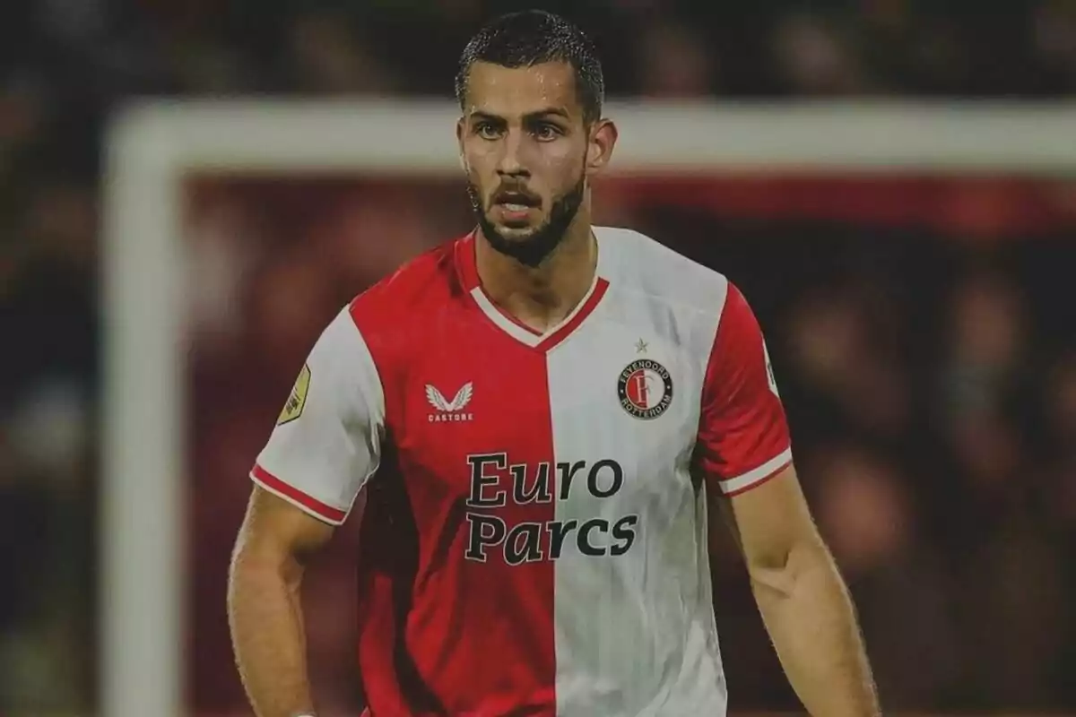 Jugador de fútbol con uniforme rojo y blanco del Feyenoord Rotterdam en el campo de juego.