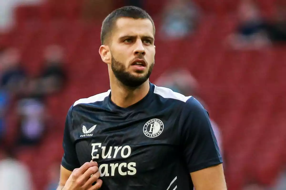 Jugador de fútbol con uniforme del Feyenoord Rotterdam en el campo de juego.