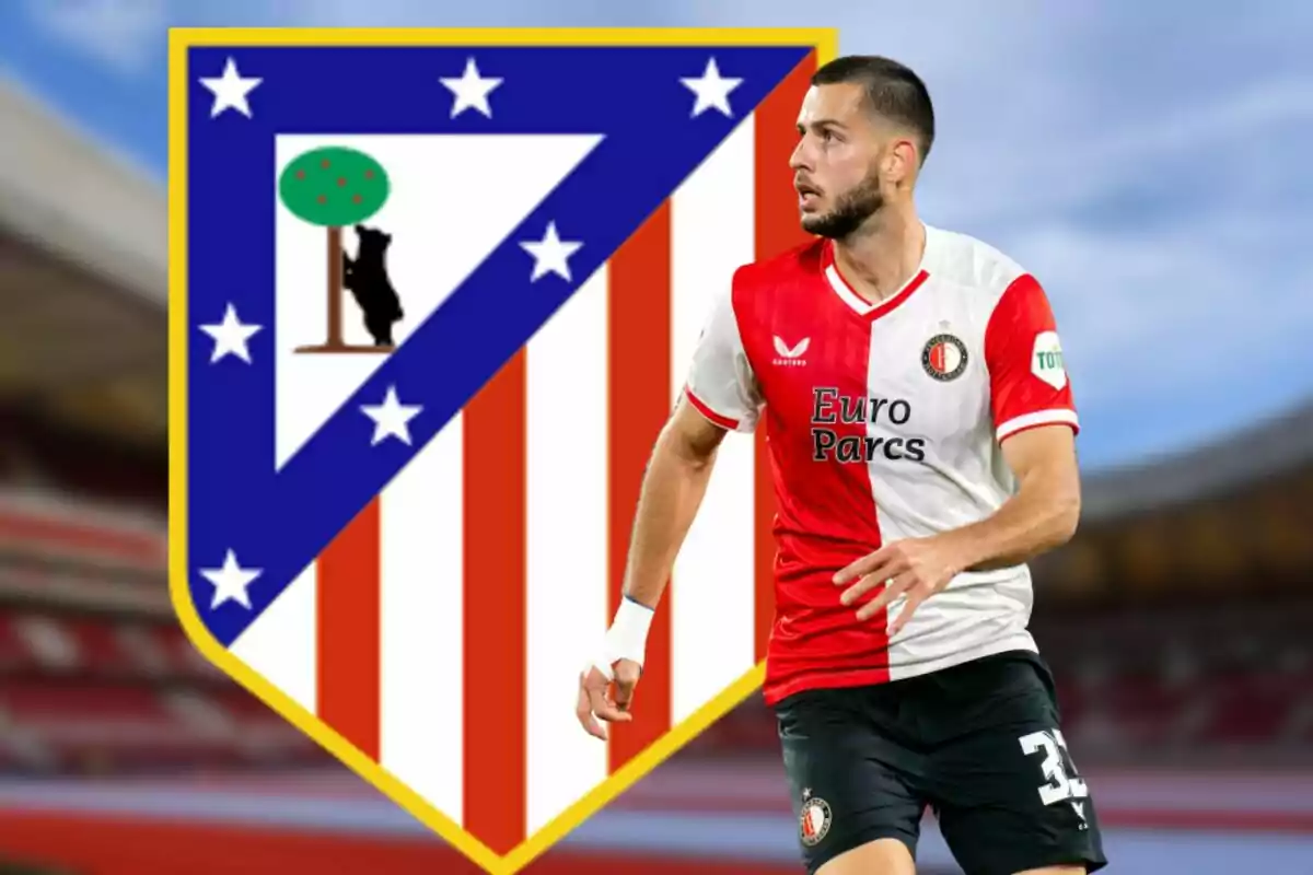 Jugador de fútbol con uniforme rojo y blanco frente al escudo del Atlético de Madrid.