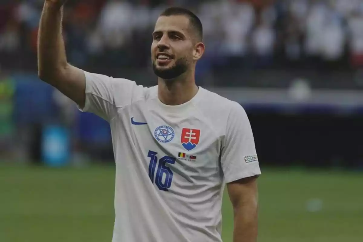 Un jugador de fútbol con la camiseta número 16 de la selección de Eslovaquia levanta el brazo en señal de saludo o celebración en un estadio.