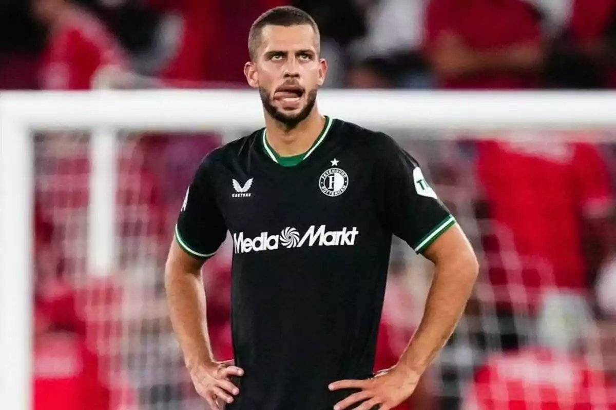 Jugador de fútbol con uniforme negro y verde en el campo de juego.