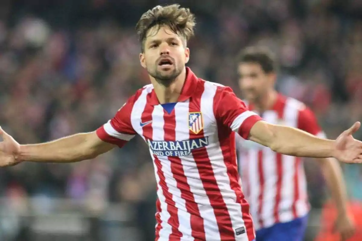 Jugador de fútbol con uniforme del Atlético de Madrid celebrando en el campo.