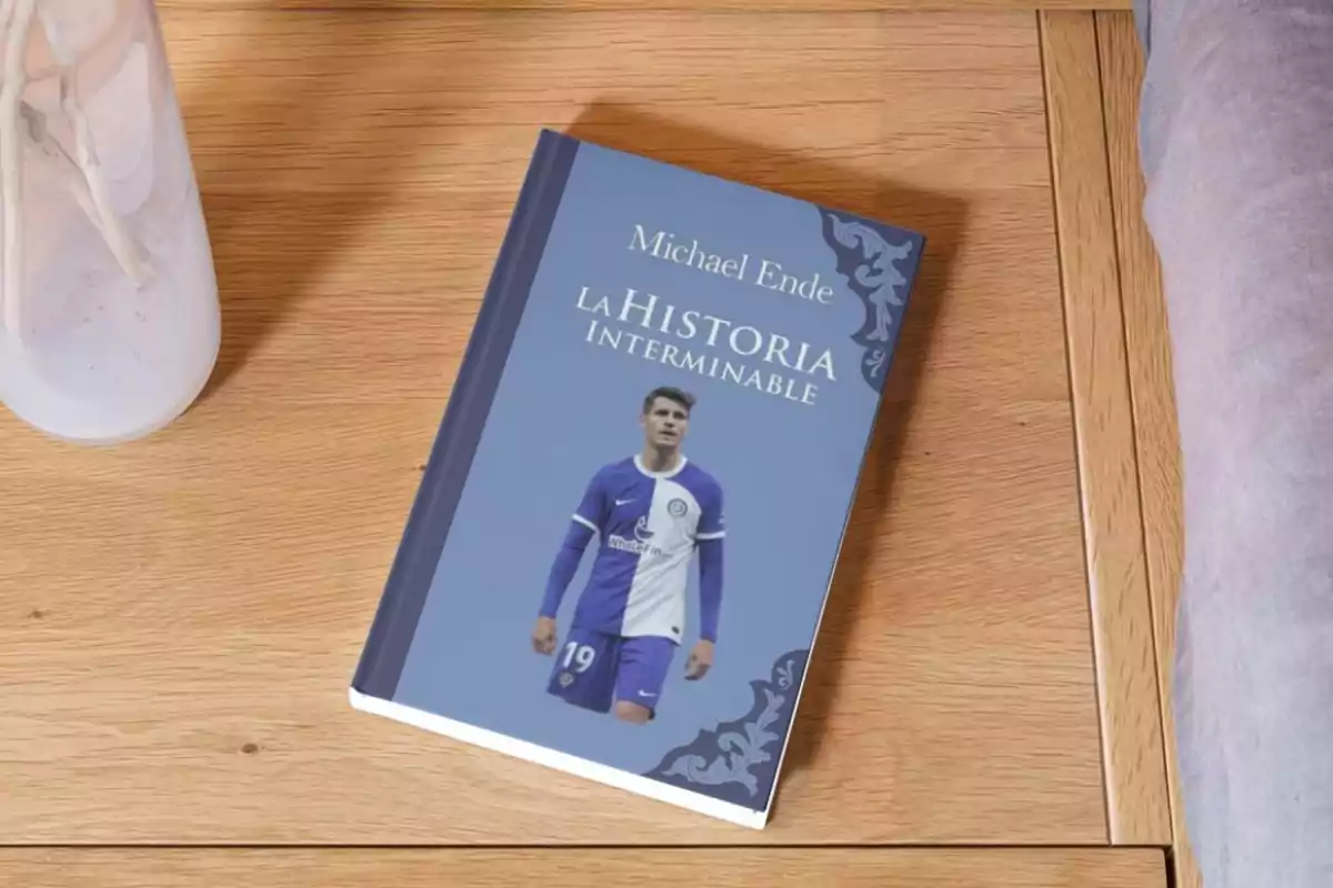 Un libro titulado "La Historia Interminable" de Michael Ende con la imagen de un jugador de fútbol en la portada, colocado sobre una mesa de madera junto a un jarrón blanco.