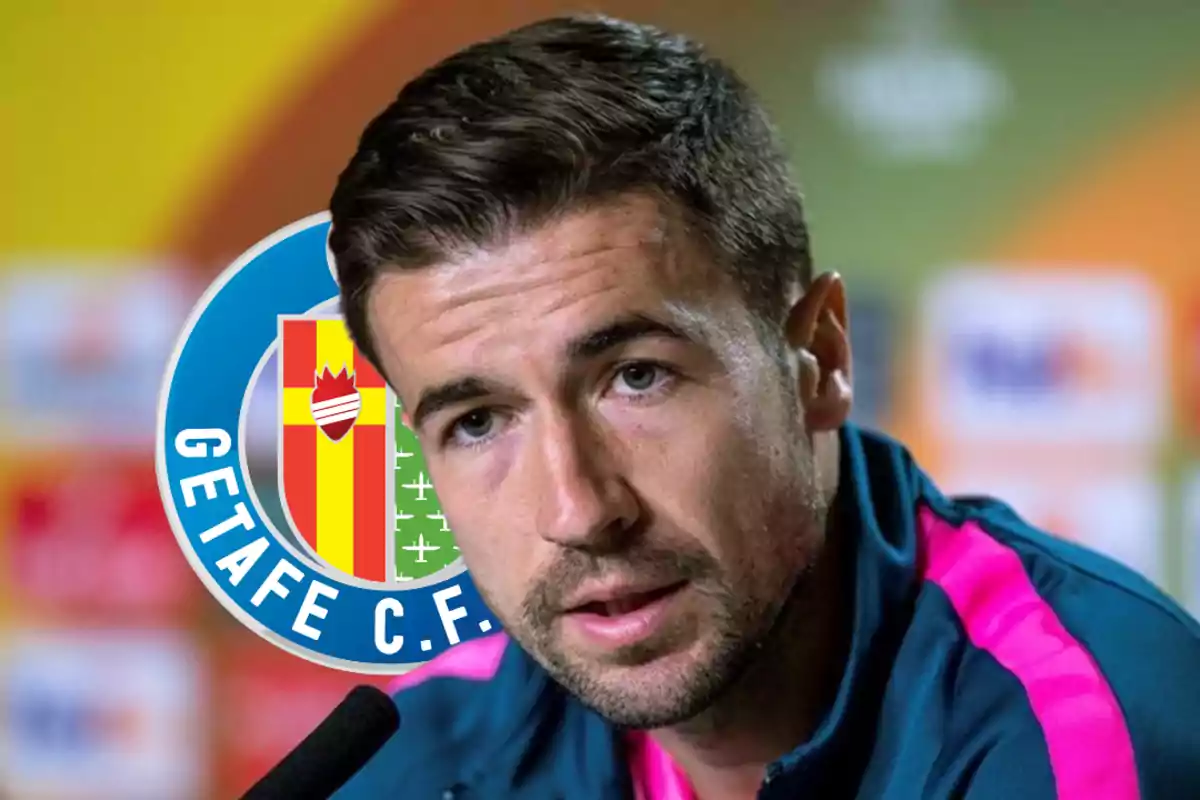 Hombre hablando en una conferencia de prensa con el logo del Getafe C.F. de fondo.