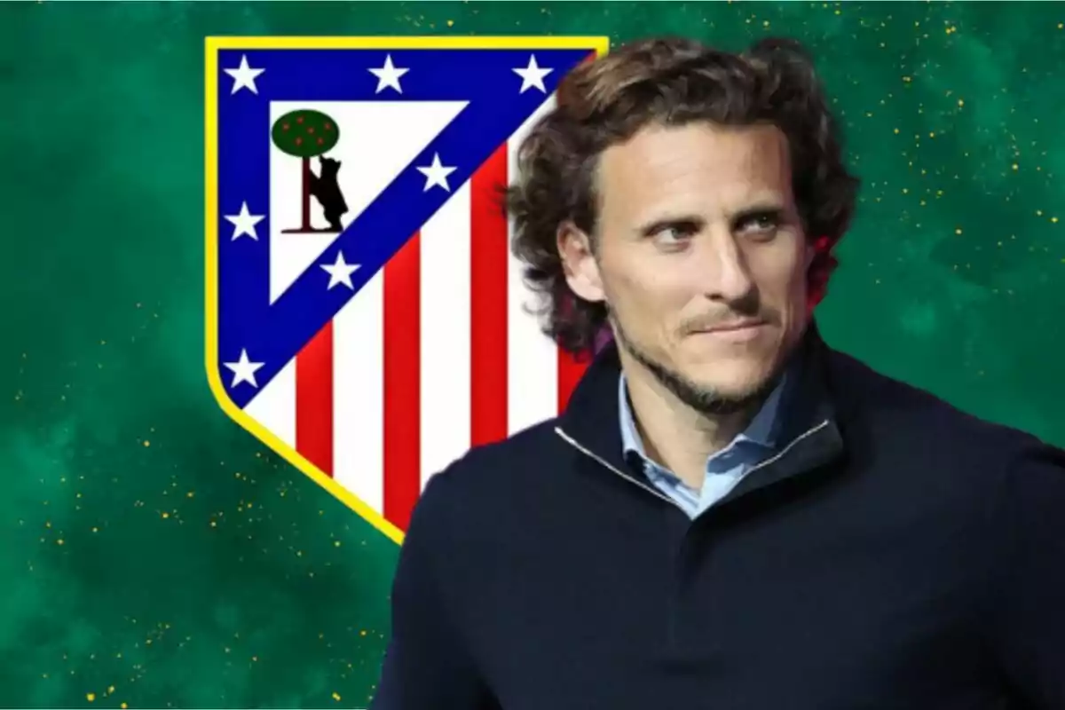 Un hombre con cabello rizado y barba ligera está frente a un escudo del Atlético de Madrid sobre un fondo verde.