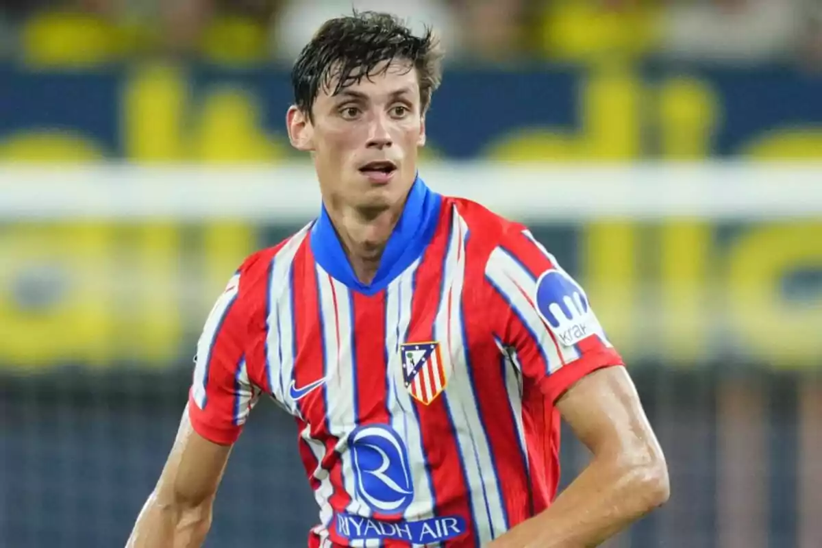 Jugador de fútbol con camiseta del Atlético de Madrid en el campo de juego.