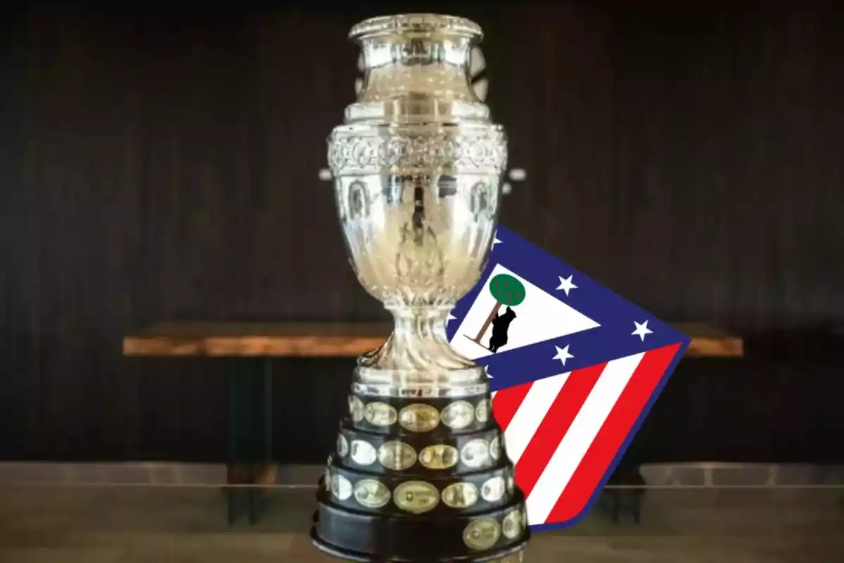 Trofeo de la Copa América con el escudo del Atlético de Madrid al fondo.