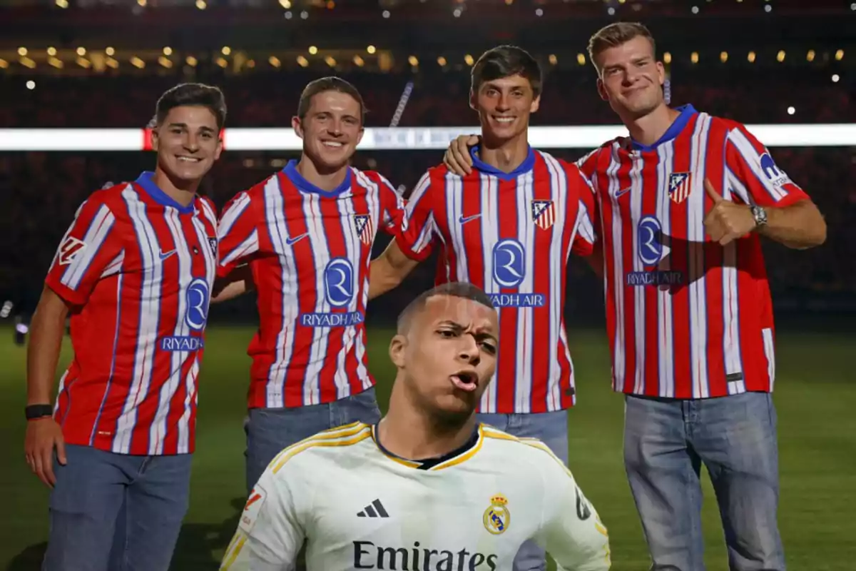 Cinco personas posan para una foto en un estadio, cuatro de ellas llevan camisetas del Atlético de Madrid y una lleva una camiseta del Real Madrid.