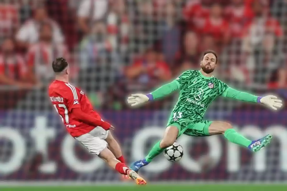 Un jugador de fútbol con uniforme rojo patea el balón mientras el portero con uniforme verde intenta detenerlo en un partido.