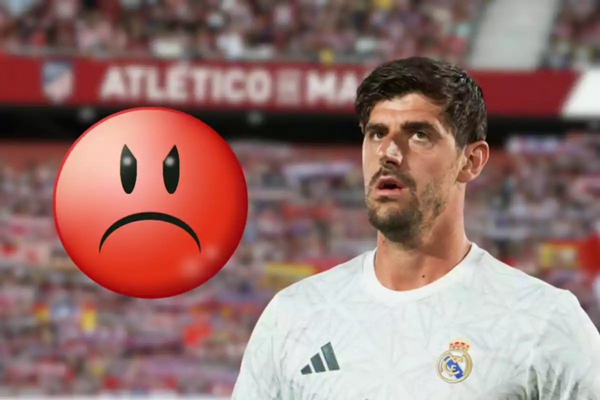 Un jugador de fútbol con una camiseta blanca del Real Madrid aparece en la imagen, con una expresión de sorpresa o desconcierto, mientras un emoji rojo con una cara de enojo se superpone en el lado izquierdo de la imagen, y de fondo se puede ver un estadio con el nombre "Atlético de Madrid".