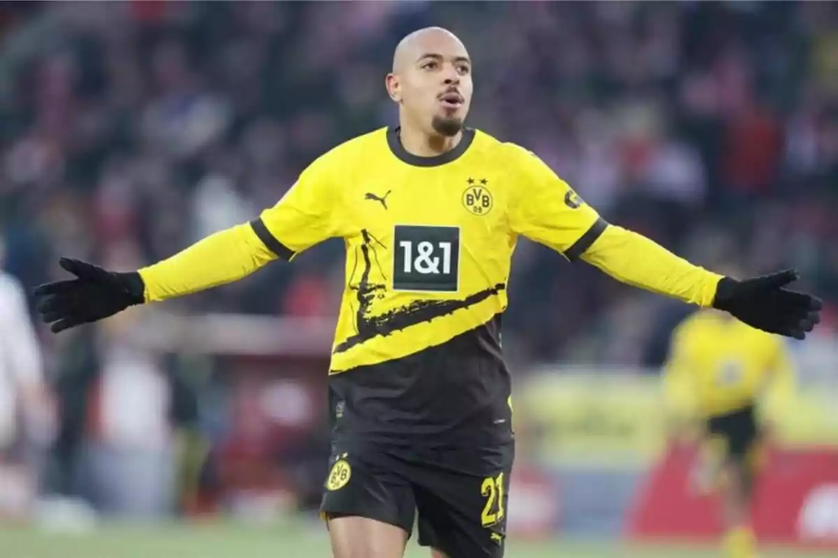 Football player in yellow and black uniform of Borussia Dortmund celebrating on the field.