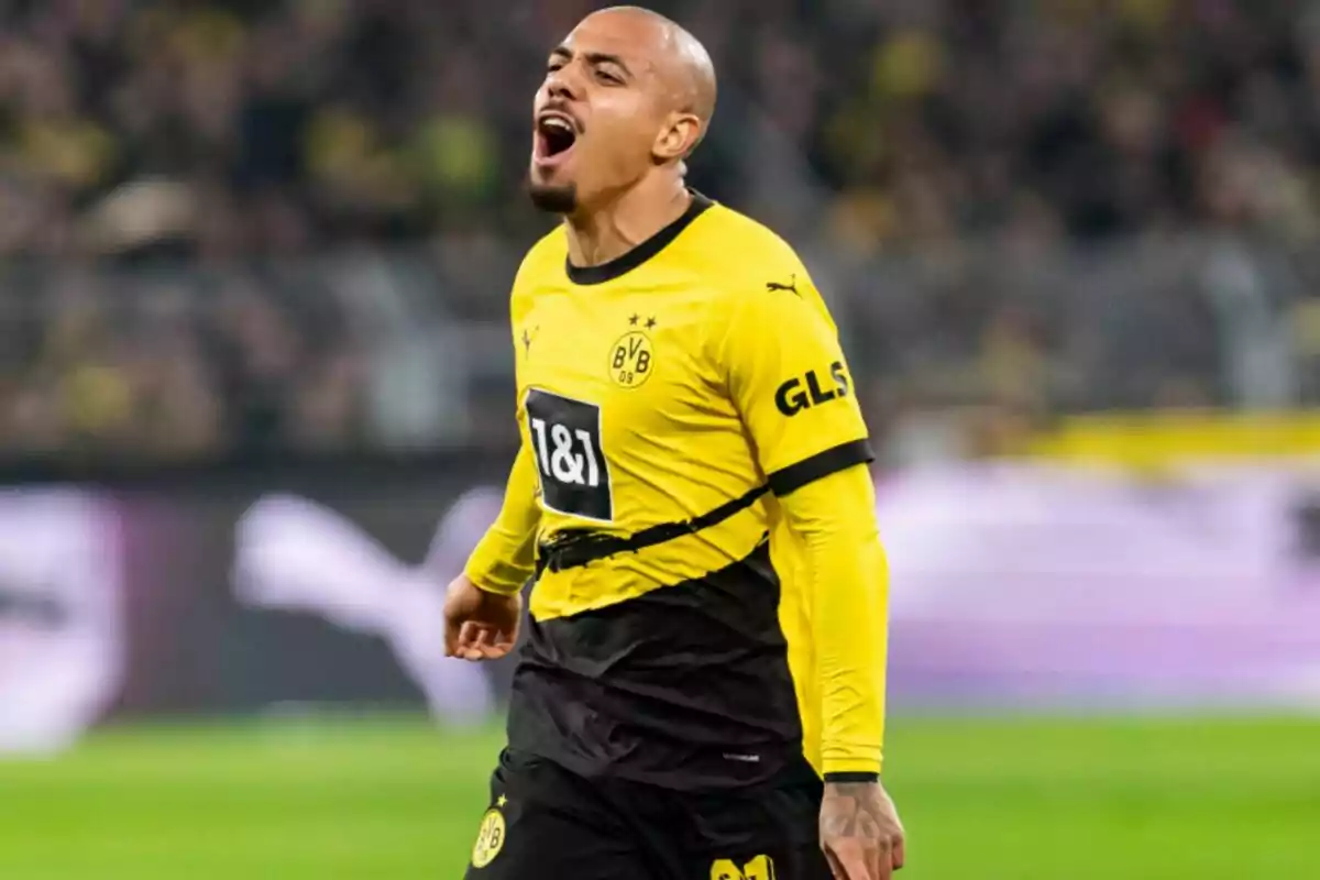 Football player in yellow and black uniform of Borussia Dortmund celebrating on the field.