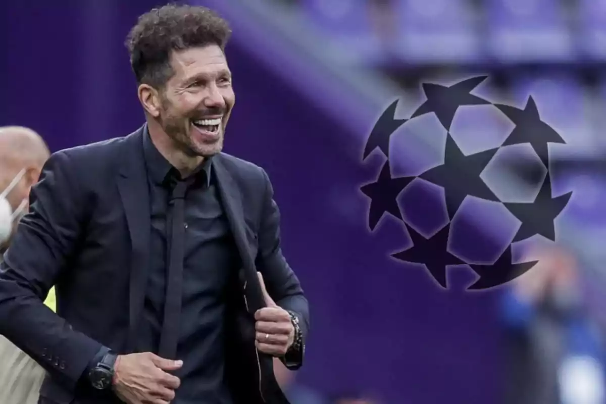 Un hombre sonriente con traje negro junto al logo de la Liga de Campeones de la UEFA.