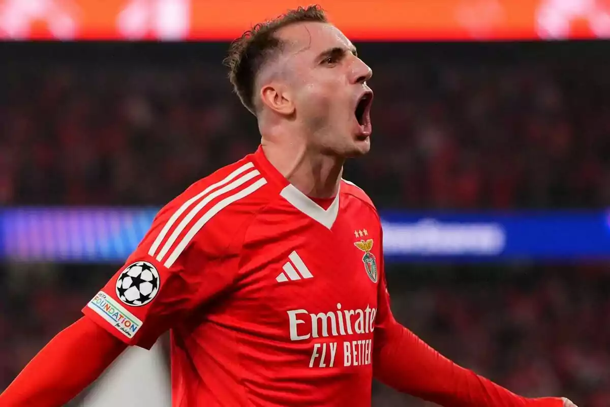 Jugador de fútbol con uniforme rojo celebrando en un estadio.