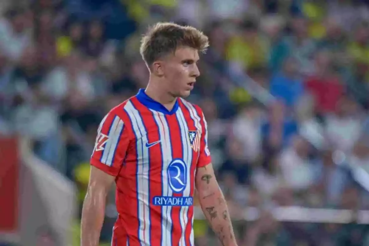 Un jugador de fútbol con uniforme rojo y azul en el campo.