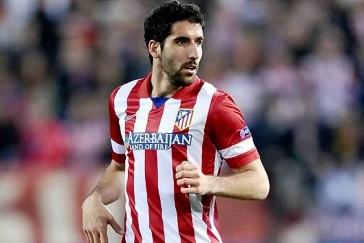 Jugador de fútbol con uniforme del Atlético de Madrid en el campo de juego.