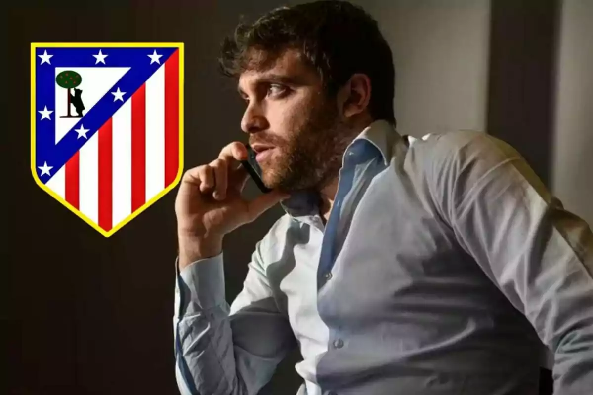 Un hombre hablando por teléfono con el escudo del Atlético de Madrid al lado.