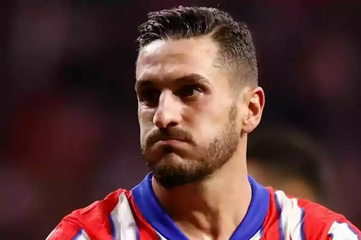 A soccer player with a serious expression and a red and white striped jersey.