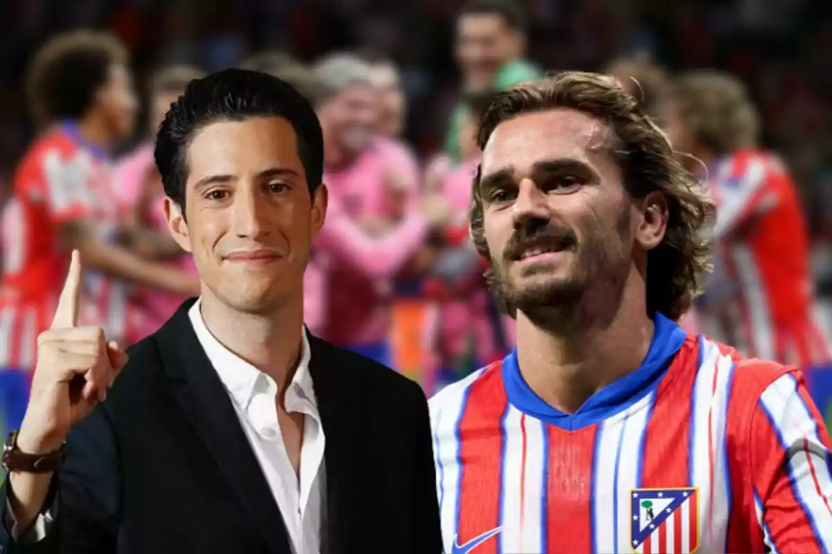 Un hombre con traje oscuro y camisa blanca levanta un dedo mientras sonríe, junto a un jugador de fútbol con camiseta a rayas rojas y blancas, con un grupo de personas desenfocadas al fondo.