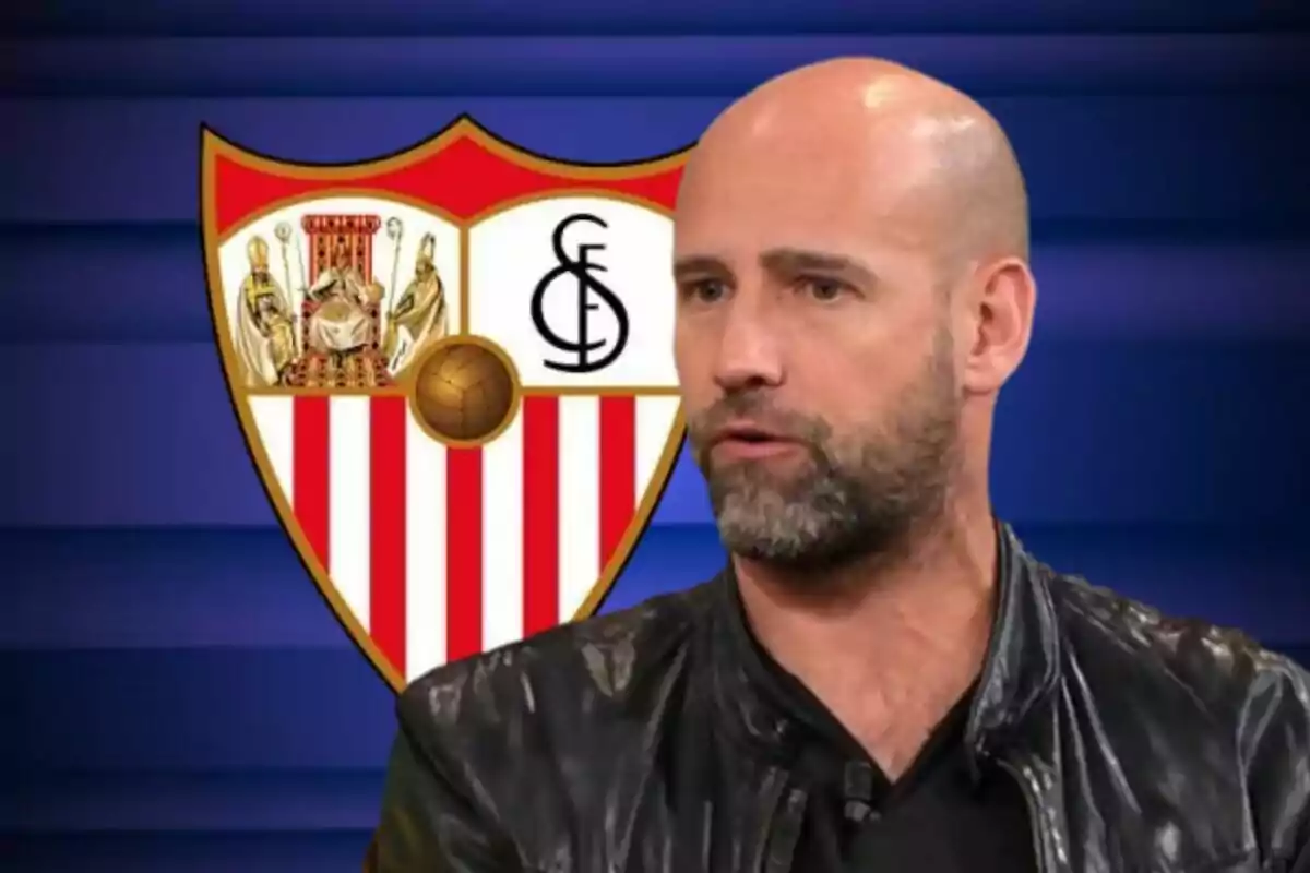 Hombre calvo con barba frente al escudo del Sevilla FC sobre un fondo azul.