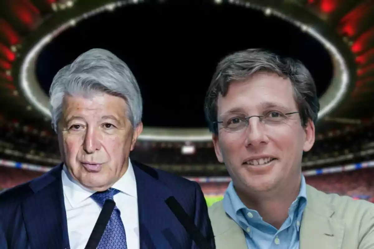 Dos hombres posan frente a un estadio iluminado.