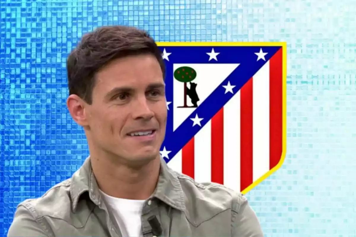 Un hombre sonriente con una camisa verde claro frente al escudo del Atlético de Madrid sobre un fondo azul.