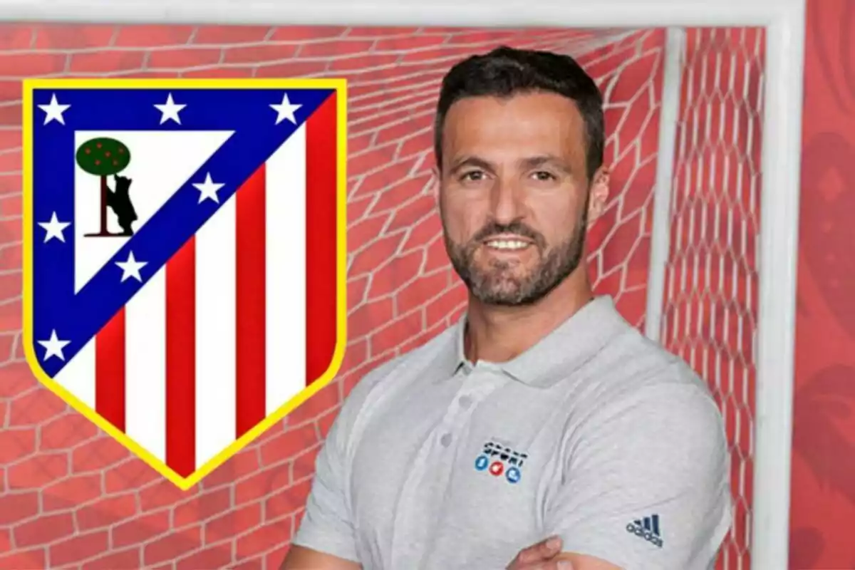 Hombre con camiseta gris posando junto al escudo del Atlético de Madrid frente a una portería.