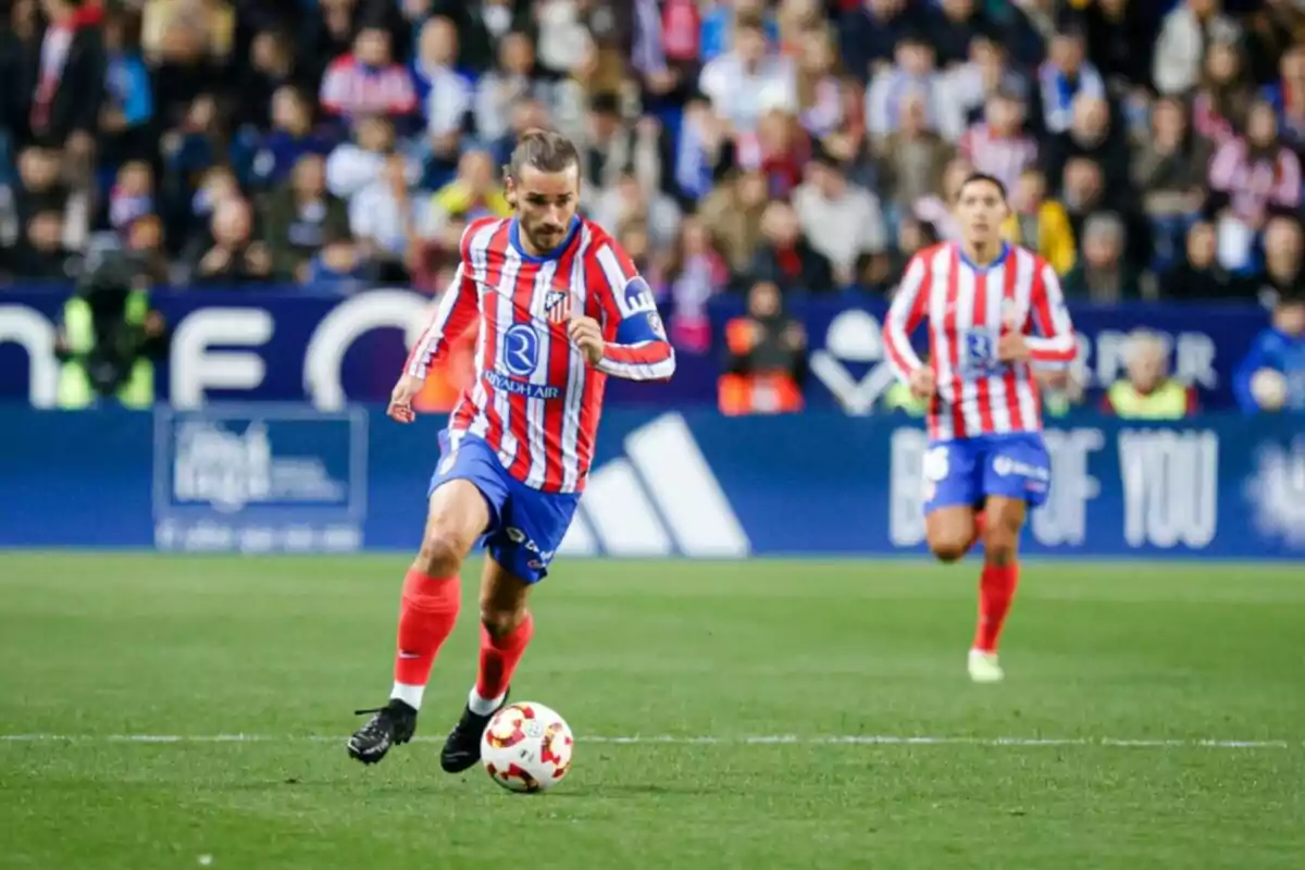 Jugador de fútbol del Atlético de Madrid corriendo con el balón en un partido.